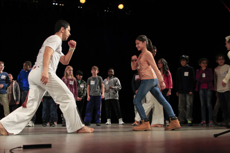 Capoeira instructor teaches student how to perform traditional Brazilian capoeira body moves.