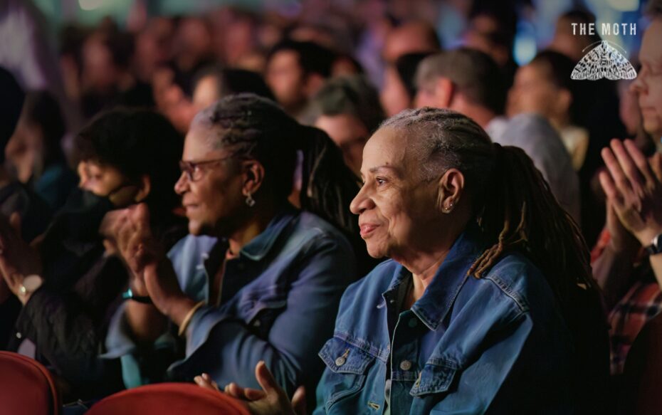 Several audience members sit in the dark theater for the performance.