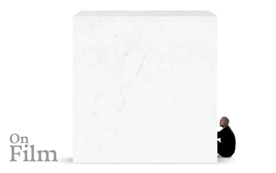 A white marble block with a man sitting next to it.