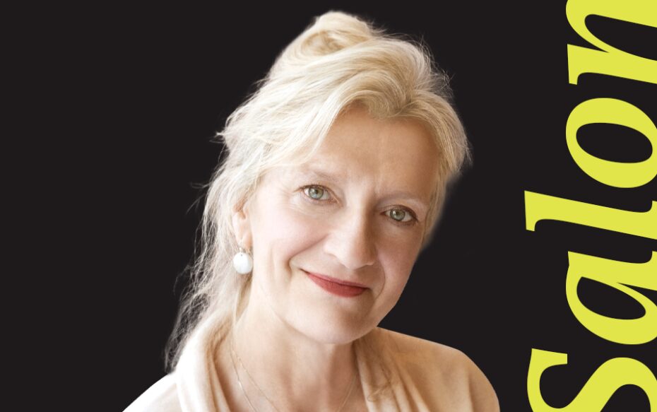 In front of a black background, Elizabeth Strout stands next to the word 'Salon.'