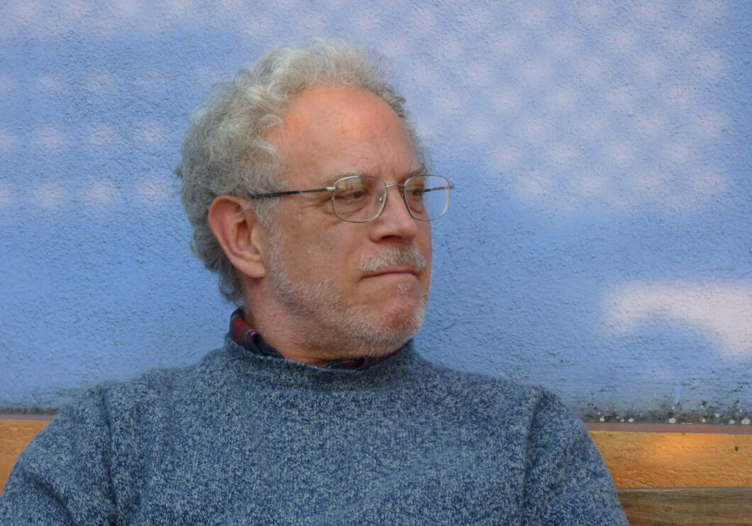 Head shot of artist Richard Festinger on blue background.