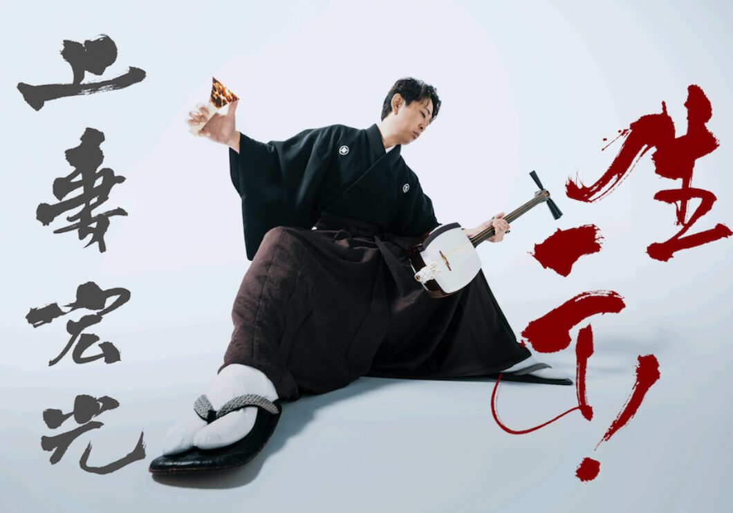 Shamisen musician Hiromitsu Agatsuma poses with shamisen in hand. The photo is shot from a low angle against a white background stylized with black and red kanji characters.
