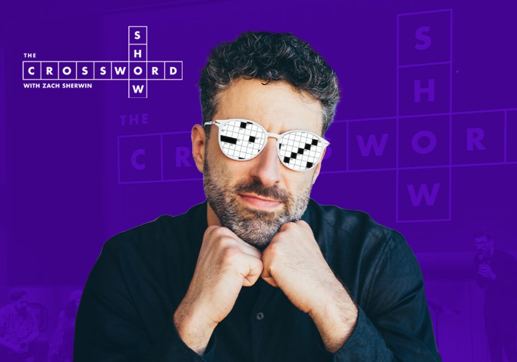 Against a purple background: a headshot of writer and comedian Zach Sherwin, wearing glasses with a crossword puzzle superimposed on the lenses. The logo for The Crossword Show appears in the upper left.