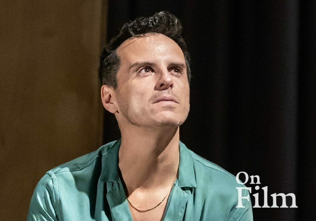 Actor Andrew Scott performing in Vanya. He is wearing a blue shirt and a gold necklace.