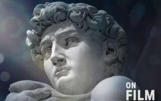 A sculpture by Michelangelo featuring the head and shoulders of a man with curly hair.