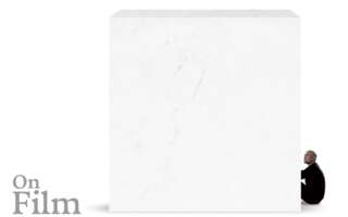 A white marble block with a man sitting next to it.