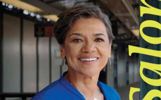 Sonia Manzano stands on a subway platform, smiling next to the word 'Salon' written in yellow lettering.